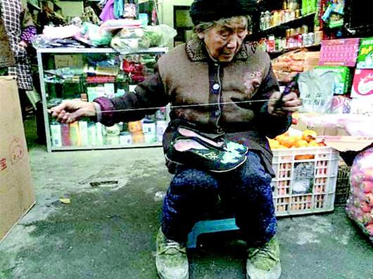 图为:86岁的秦光萍婆婆白天喂猪、操持家务,晚上抽空做布鞋,自己穿针引线。