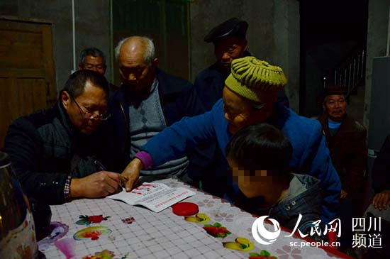 村民正在“联名信”上签字按手印,坤坤在仔细的看着。(陈永斌摄)