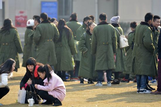 圖為候考的考生身穿軍大衣抵御寒風(fēng)。