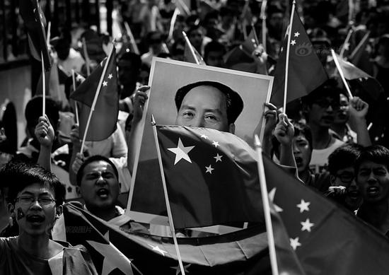 2012年9月16日,湖北武汉,保卫钓鱼岛游行。激昂的学生手举毛泽东纪念像和五星红旗。