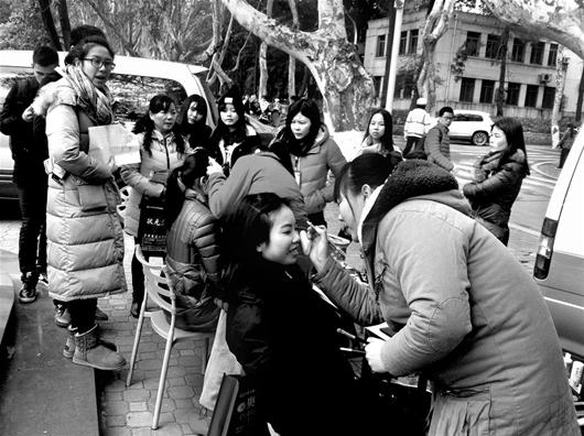 图为:考生们迎着寒风,现场化妆(记者赵莉摄)