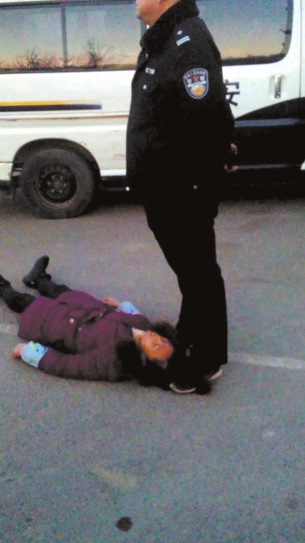 事发现场一名身穿警服的男子疑似用脚踩着女农民 工周秀云的头发