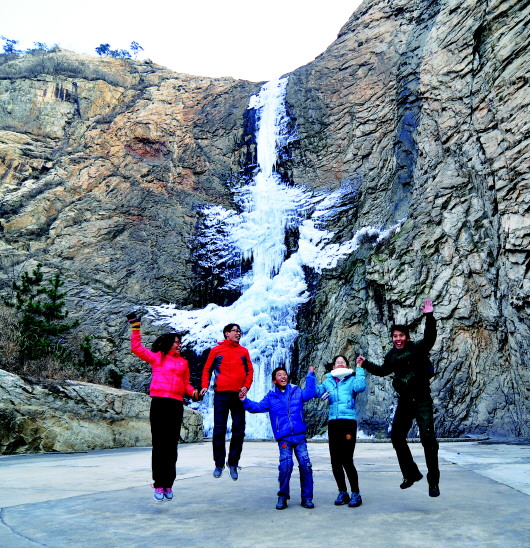 1月3日，游客在日照五莲县七连山风景区内一处数十米高的冰瀑前拍照游玩。