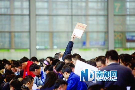 办证人群中,一名男子高举档案袋招呼同伴。南都记者 王子荣 摄