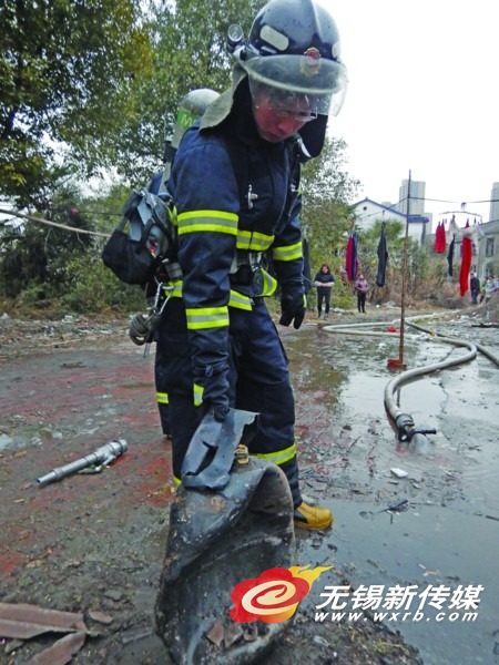 消防员从失火房屋内取出已变形的液化气瓶。