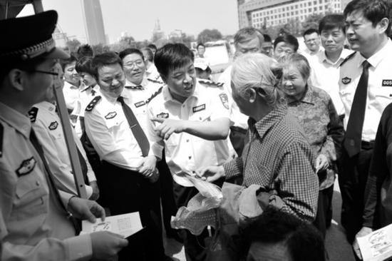 就任濟南市公安局局長期間,劉新云(中)在街頭向市民講解放高利貸等經濟犯罪的危害(資料片)記者劉暢攝