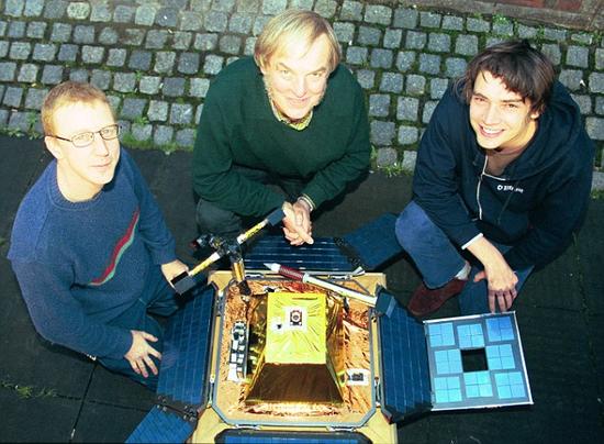 猎兔犬-2号探测器发射前夕，英国流行乐团“污点乐队”成员Dave Rowntree(左)和Alex James(右)与科林·菲林格博士(中间)在一起。污点乐队创作了猎兔犬-2号飞船的呼叫音乐