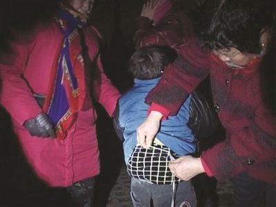孩子腰部被拴着绳子捆在石凳上,市民为他解绳子。