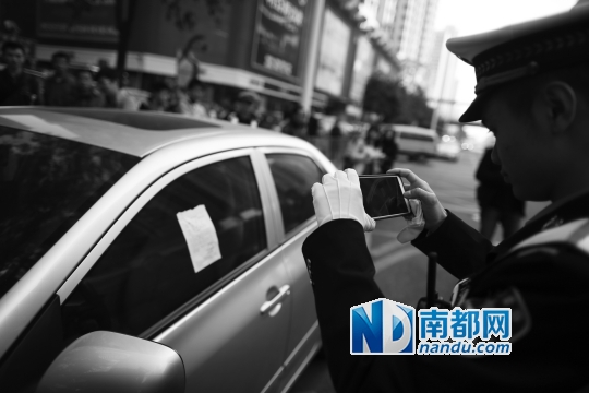 昨日,交通督导员在严管区对违停车辆拍照取证。南都记者 王子荣 摄
