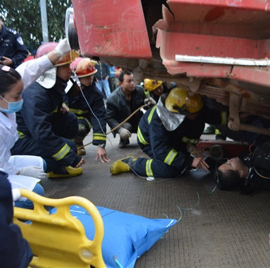 消防人员正在营救被困车底的女子。