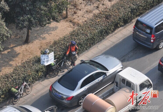 两名骑行装束的外地男子，举着求助纸张沿街乞讨。