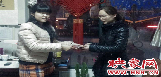 郑州快速公交公司B23路调度员李艳艳(左)在调度室将失主杨女士(右)遗失的钱物归还给失主