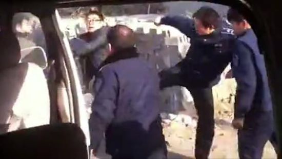 多名身著疑似城管制服的男子，在一輛疑似警務面包車旁，對一名男子拳打腳踢。 視頻截圖