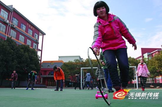 扬名中心小学学生在玩滚铁环