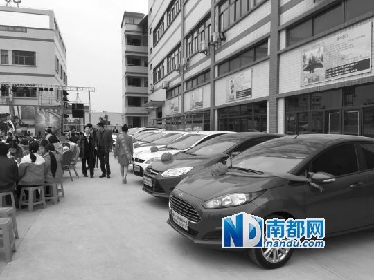 工厂大院里摆起宴席,边上停着11辆即将发放的新车。
