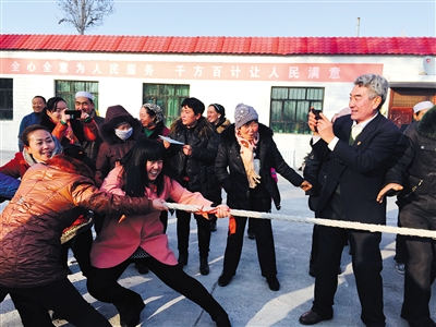 1月29日，张泉年组织村民参加赛跑、拔河等比赛。张泉年举着手机，抓拍比赛瞬间。新京报记者 高美 摄