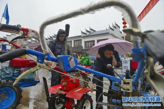  2月27日，新建县西山镇农民在科技下乡活动上查看农机。