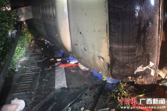 图为事故现场1名乘客被压在侧翻的大客车下面