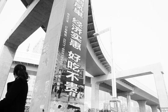 郑州北环路与文化路交叉口,六根高架桥桥墩都被贴上了“巨幅”广告