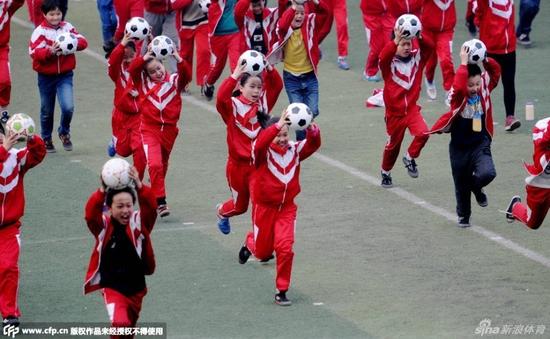 河南洛阳:校园足球普及 学生抱着足球跳操