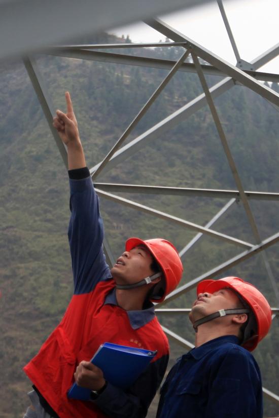 国网湖南电力员工员工在正负800千伏宾金线0923号铁塔上对绝缘子进行喷涂作业（黄瑶 摄）