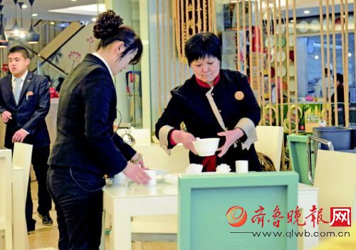 24日,济南某餐厅服务员(右一)正在收拾桌子,记者走访多家餐厅发现,像这样40多岁的服务员并不少见。记者 郭建政 摄