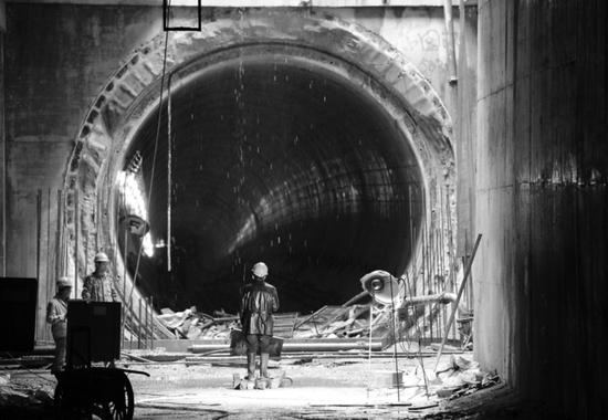 在地铁1号线徽州大道站一处隧道口，工人们正在施工，为铺轨做准备。