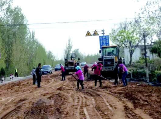 17日,鲁宁高压输油管线被挖坏,附近道路洒满原油,图为工人正在用黄土清理。本报记者　张伟　摄