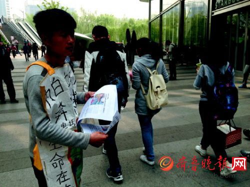 代远红向过往的行人发放募捐求助宣传单。