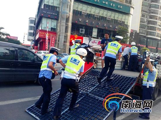 交警正拖动违规停放的电动车(南海网记者刘培远摄)