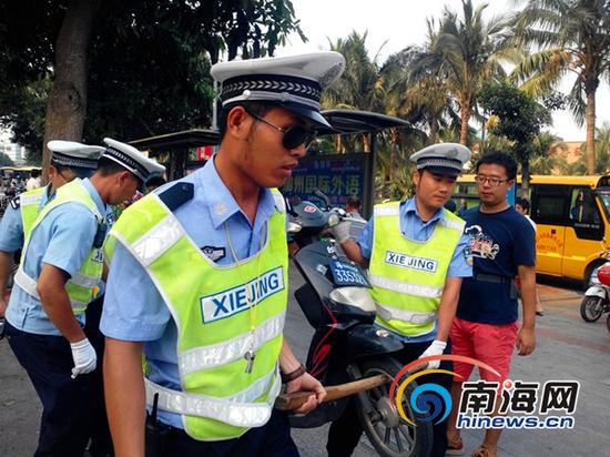 交警正拖动违规停放的电动车(南海网记者刘培远摄)