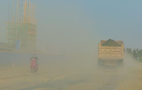 北三環一工地附近，騎電動車的男子被灰塵“淹沒”。
