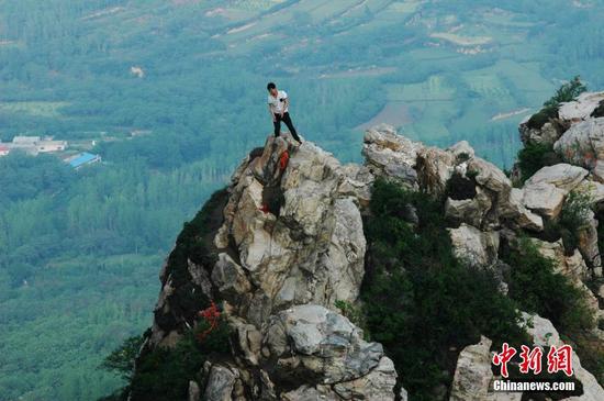 郑州景区游客爬百米悬崖绝壁 拍照留影