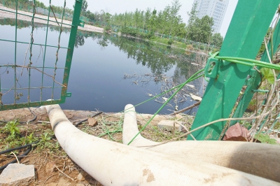 通過兩根白色的管子，大量污水被從積水池中抽出。