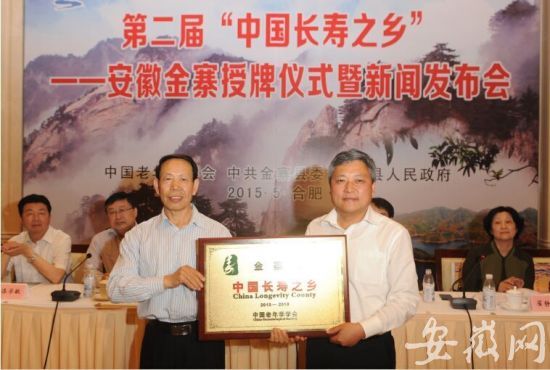 金寨县委副书记、县长汪冬(右)从中国老年学学会常务副会长赵宝华(左)手中,接过“中国长寿之乡”牌匾。