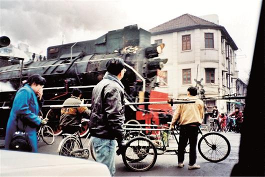 图为：上世纪90年代初，一辆蒸汽机车驶过汉口闹市