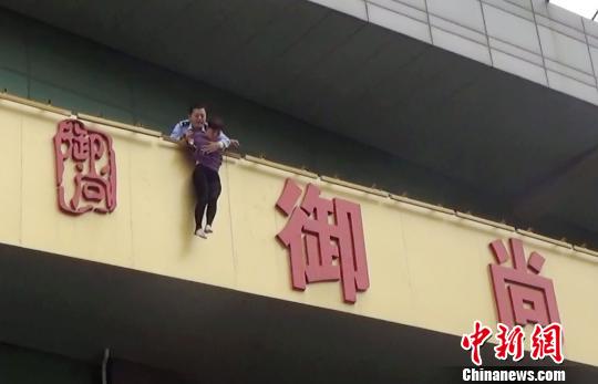 8日下午4点多，烟台经济技术开发区内一重庆女子欲跳楼，正当该女子滑落平台的一瞬间，一名民警冲上前将她紧紧抱住，挽救了女子性命。　张德新　摄