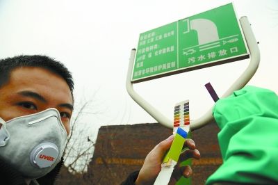 江守望者用便携式仪器检测水质，旁边是湘潭市环保局树立的排污公示牌。 通讯员 摄