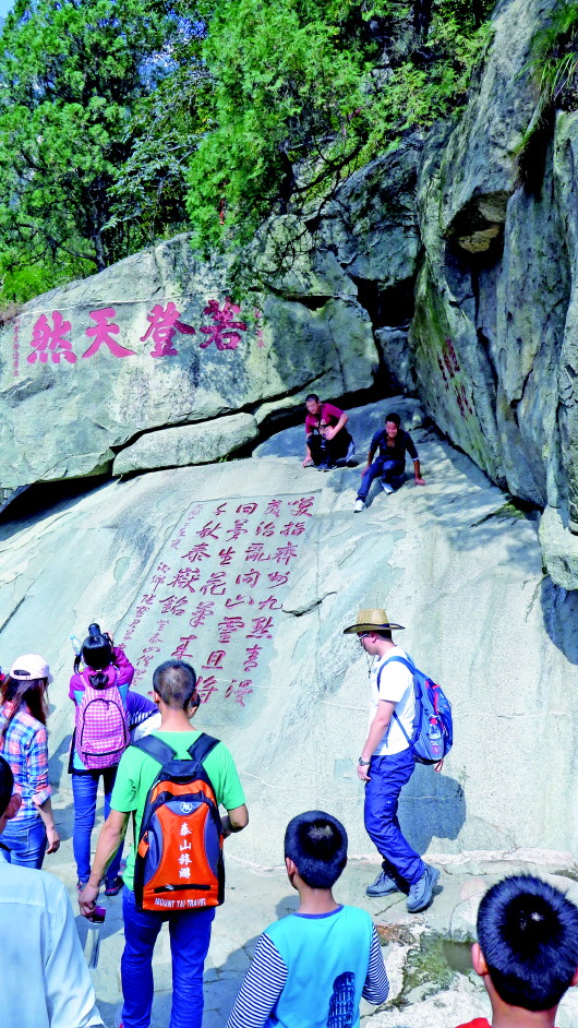 泰山登山路上,一些游客攀登摩崖石刻照相。　　　　　　　　　　　　　本报记者　乔显佳　摄