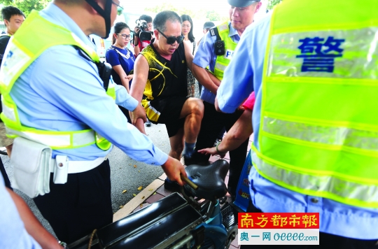 昨日,广州治理“五类车”,中山大道,交警拦截住一位骑电瓶车买菜的老人,在求情不成后,老人家开始踢电瓶车,他称,宁愿踢烂了也不愿意被收缴。南都记者 陈坤荣 摄
