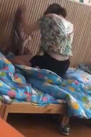 女教师跨坐小孩身上,双手捆住小孩猛打。视频截图