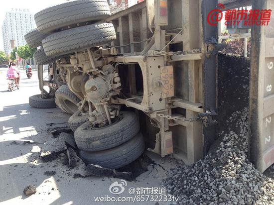秦岭路与北环路交叉口向南500米，一辆载有建筑材料的大货车，经过此处时路面突然塌陷，整个后轮都陷了进去，货车侧翻在路上，连旁边学校的围墙也被砸塌了。