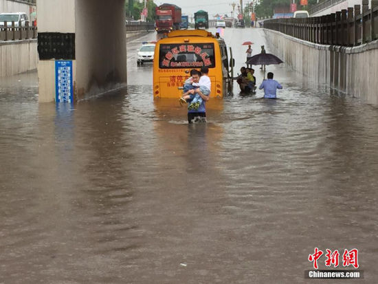 江西突降暴雨校车被困，交警涉水转移29名幼儿。