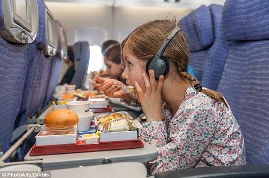 美国研究人员发现，在一架有噪音的飞机上，甜味变得不再那么甜，但鲜味食物的味道在喧闹环境中变得更强烈。照片显示，一个小女孩正在吞吃飞机餐。
