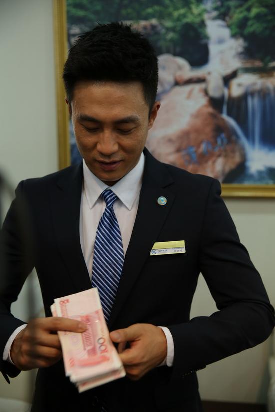 饰演银行职员的杜淳在演示数钞票