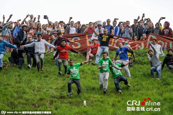 参赛选手在比赛中追赶一个从陡坡上滚下的巨大奶酪轮，“奶酪勇士”们就算被摔断胳膊和腿也在所不惜。