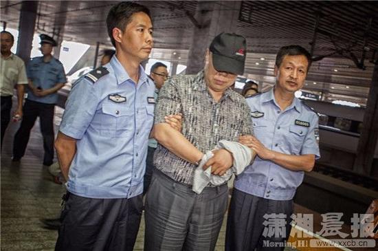 5月27日，长沙武广高铁站，长沙警方押送涉嫌合同诈骗犯罪的嫌疑人刘伟华。图/潇湘晨报记者 张迪