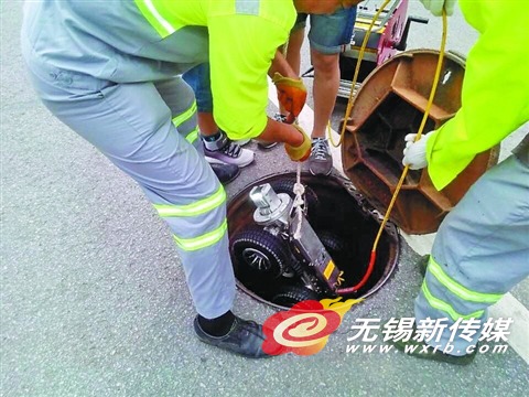 市政养护工人将检测机器人放入井内,准备工作。