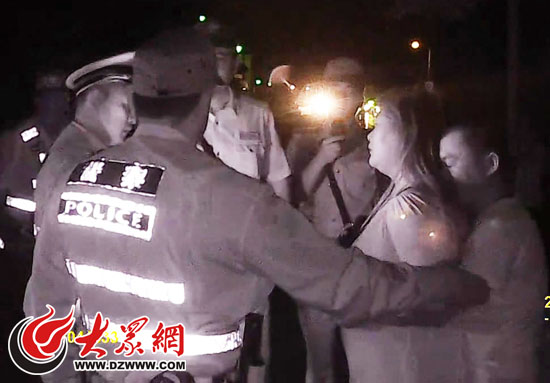 李某用身体挡住丈夫赵某，试图阻止民警执法。（执法记录仪画面截图）