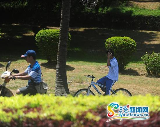 6月4日，一学生双手不扶车龙头骑行在三亚凤凰路上。(三亚新闻网记者沙晓峰摄)